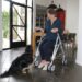 A woman is sat on her walker, she is in a kitchen and looking down at a dog at her feet to represent let's talk about mobility aids