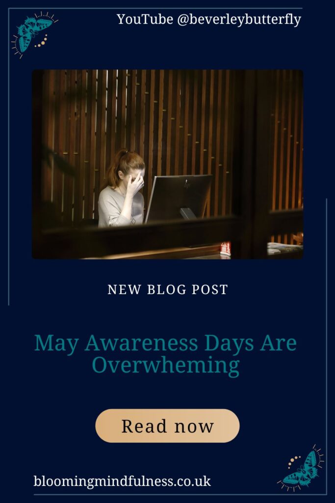 A woman is sitting behind a computer in an office she has her hand on her head looking overwhelmed to represent May Awareness Days Are Overwheming