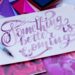 an artists desk is seen, on it someone has painted on white paper 'something better is coming' in purple writing to represent Affirmations for the Illness Journey