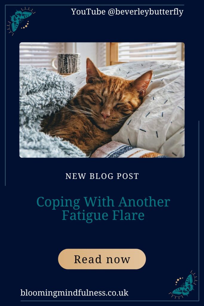 A ginger cat snuggled up in bed, head on pillow and cosy blanket, behind them on the bedside table is a mug of a lovely hot drink very cosy scene to represent coping with another fatigue flare