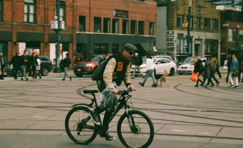 someone is seen cycling on a road in a city they are wearing a helmet and a backpack