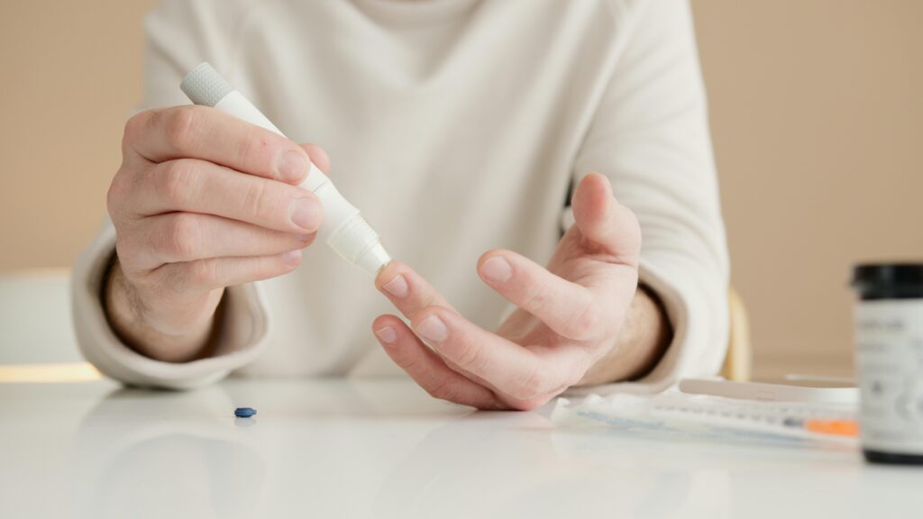 A person is seen using a pen shaped instrument to prick their finger and take blood sugar readings 