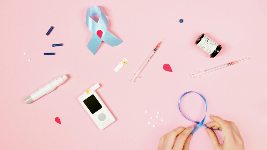 a pink background showing illness equipment and a persons hands looping blue ribbon