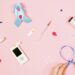 a pink background showing illness equipment and a persons hands looping blue ribbon