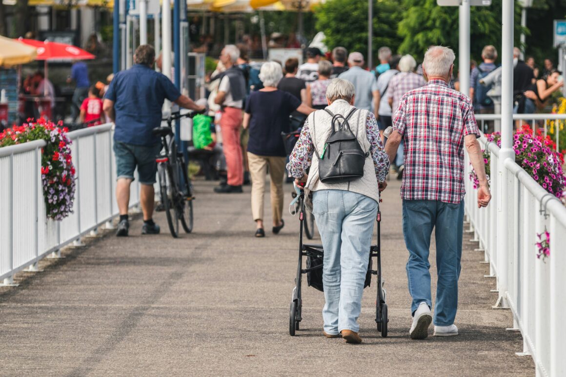 Two people are walking on a crowded street one with a walker to represent pain awareness month 2025