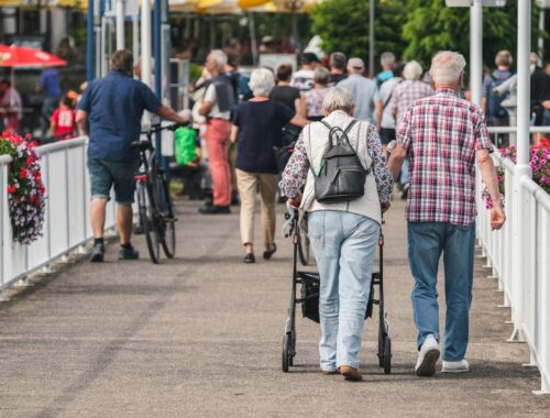 Two people are walking on a crowded street one with a walker to represent pain awareness month 2025