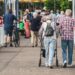 Two people are walking on a crowded street one with a walker to represent pain awareness month 2025