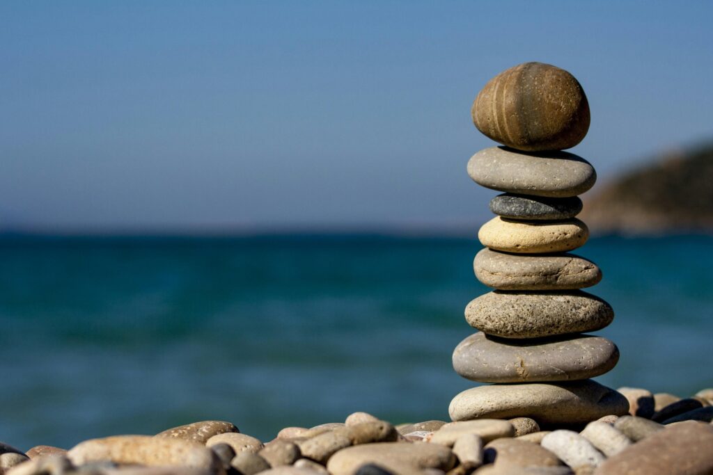A pile of stones are seen on a beach with blue skies and the sea behind