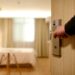 A person's hand is seen on an open doorhandle leading into a beautiful hotel room