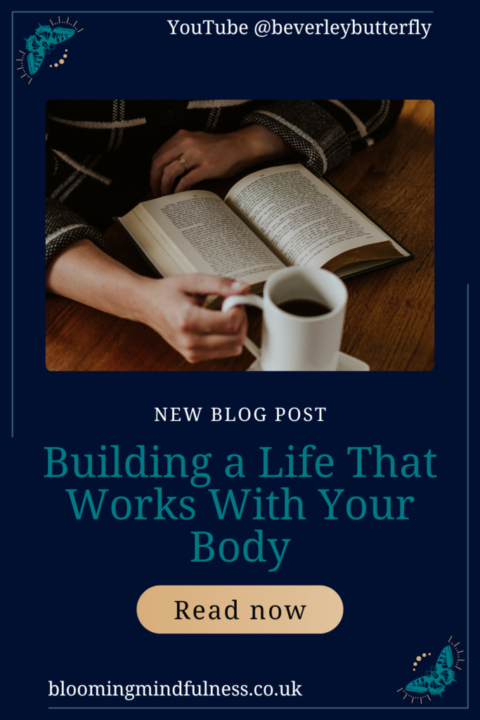 A table is seen with someone holding a cup of hot beverage and reading a book to represent Building a life that works with your body